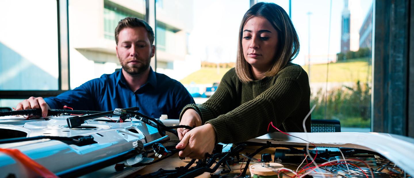man and woman working on an electrical circuit board with wires